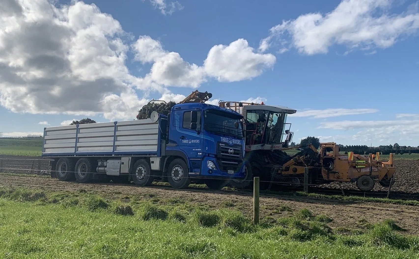 Three Rivers Contracting truck loading fodder beet alongside a harvester in a Southland field.