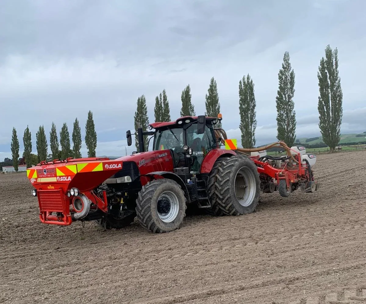 Harvest and spreading machinery working in a paddock.